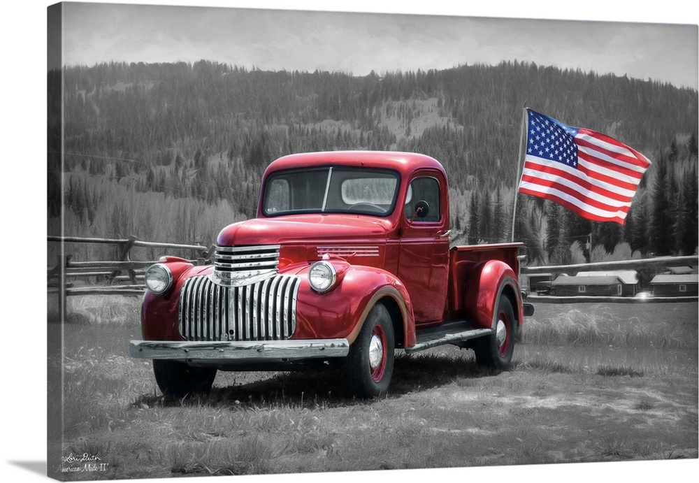 A vintage red truck with an American Flag in a field in the countryside.