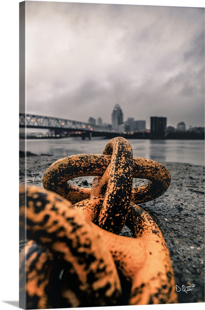 Close up photograph of worn rusted chain with cityscape in the background.
