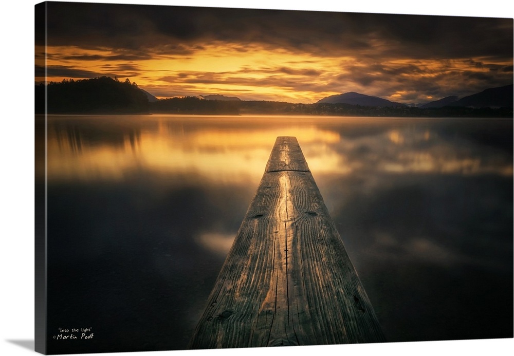 A wooden pier stretching into the water against golden light from the setting sun.