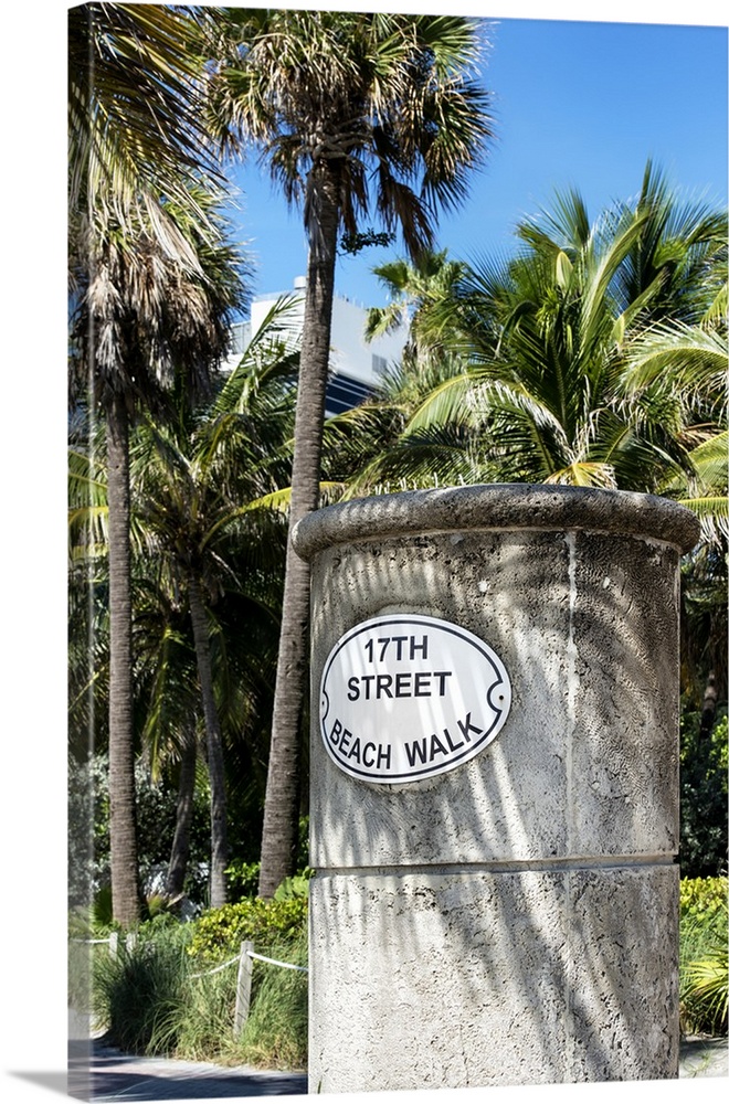 A stone sign for the Beach Walk in Miami, shaded by palm trees.