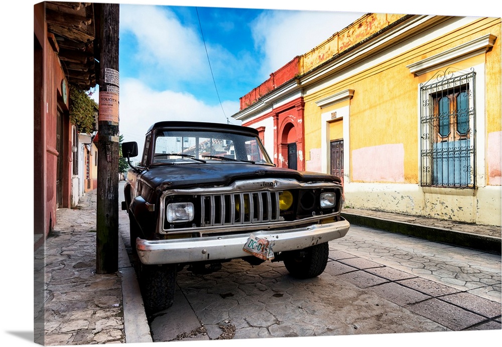 Photograph of an old black Jeep parked on the side of a colorful street in Mexico. From the Viva Mexico Collection.