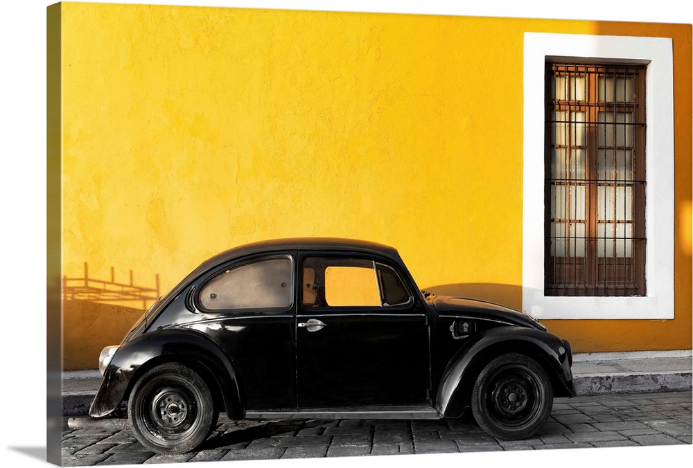 Photograph of a black Volkswagen Beetle parked on the street in front of a gold exterior wall. From the Viva Mexico Collec...
