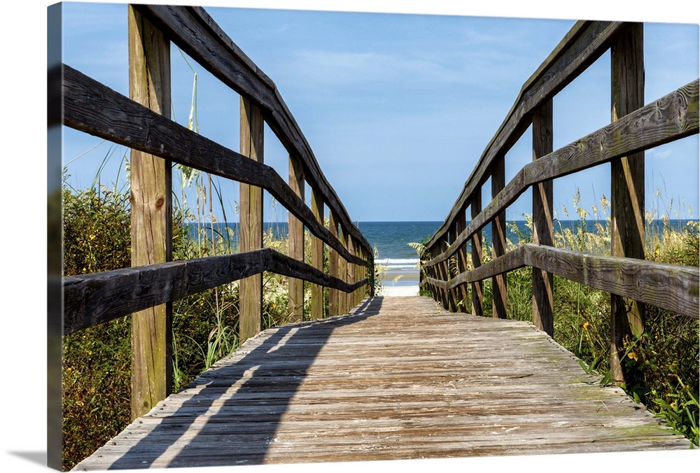 Wooden boardwalk leading to the sandy beach on the coast.