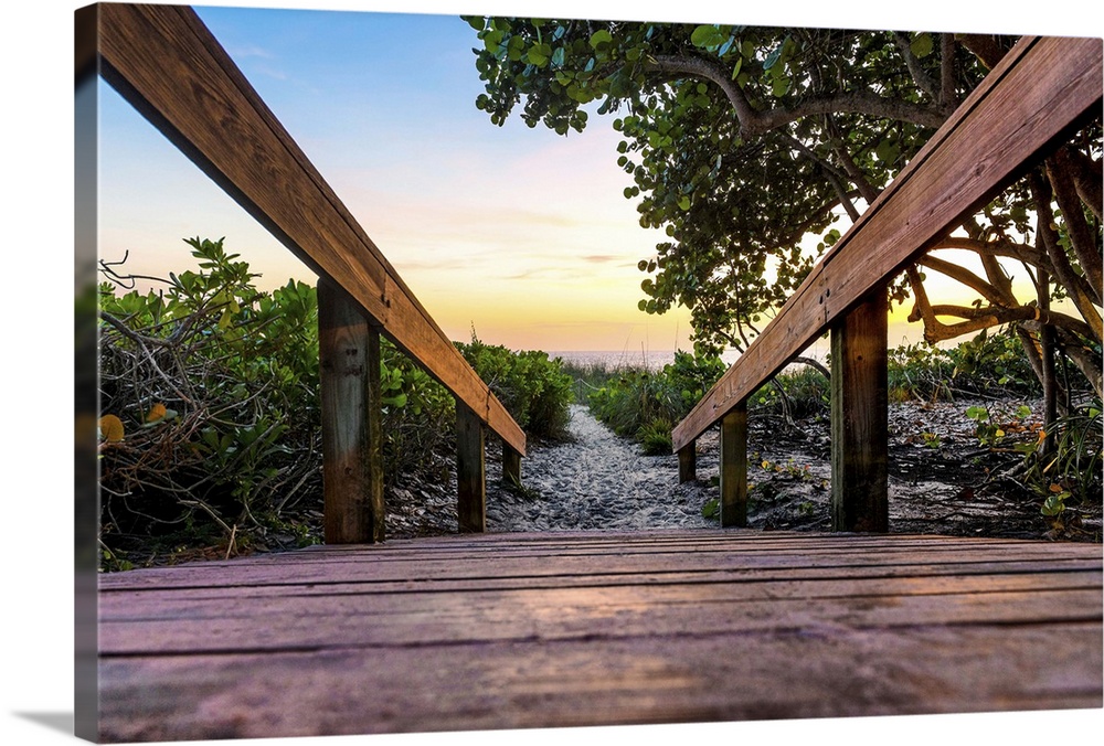 View from the ground on a wooden walkway leading to the sand at dusk.