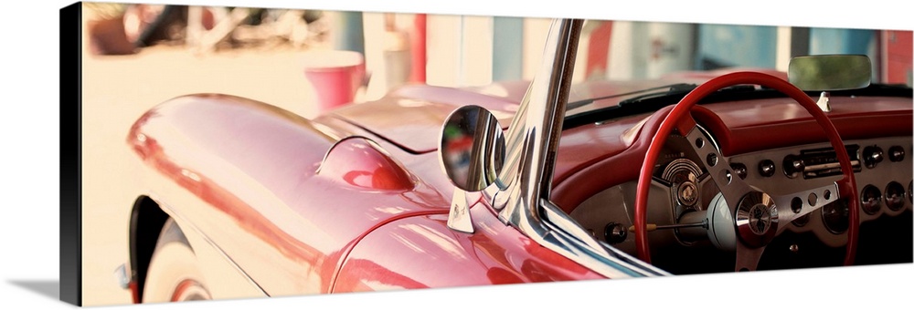 The cherry red steering wheel stands out in this classic Chevy convertible on the beach.
