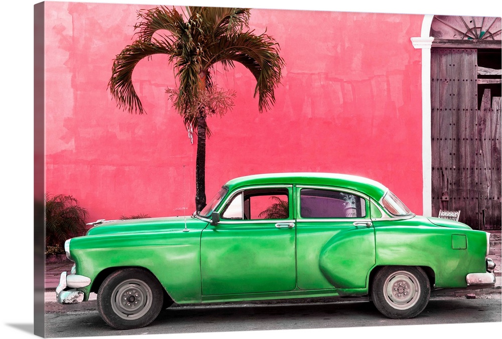 Photograph of a green vintage car parked outside of a bright pink building with a palm tree.