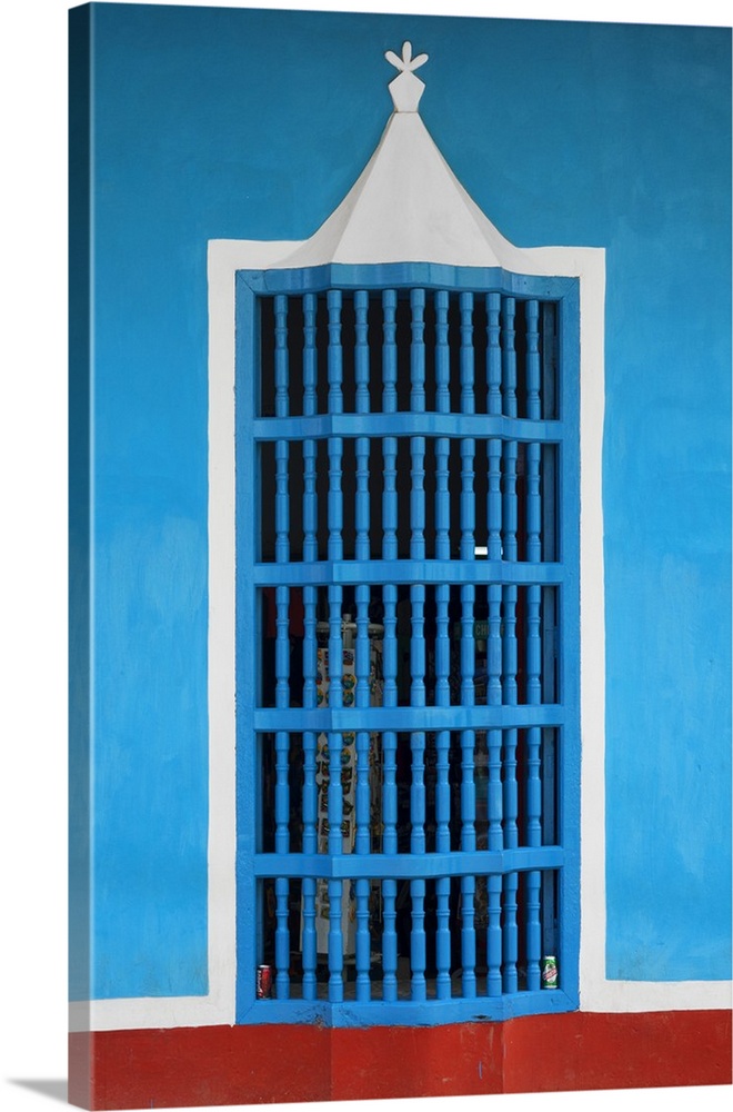 Photograph of a blue, white, and red facade with a decorative window in Havana.