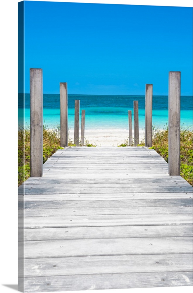Photograph of a wooden boardwalk leading straight to the crystal blue ocean in Cuba.