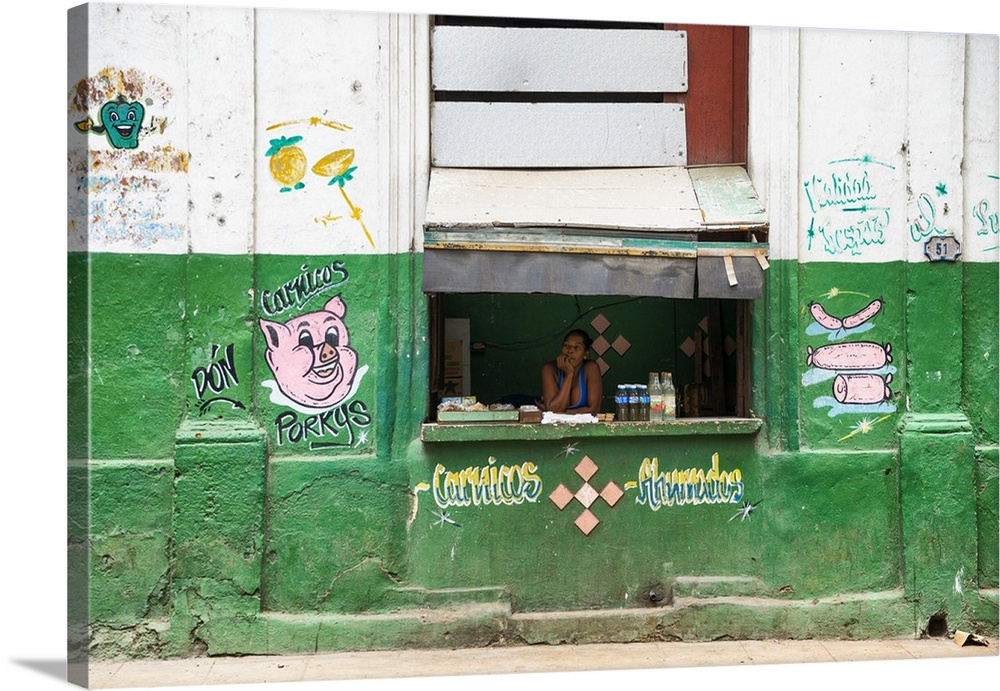 Photograph of a "hole in the wall" meat stop with a woman working the counter in Havana, Cuba.