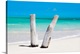 image thumbnail of Photograph of two pieces of driftwood standing up in the white sands of a Cuban beach with the ocean in the background.