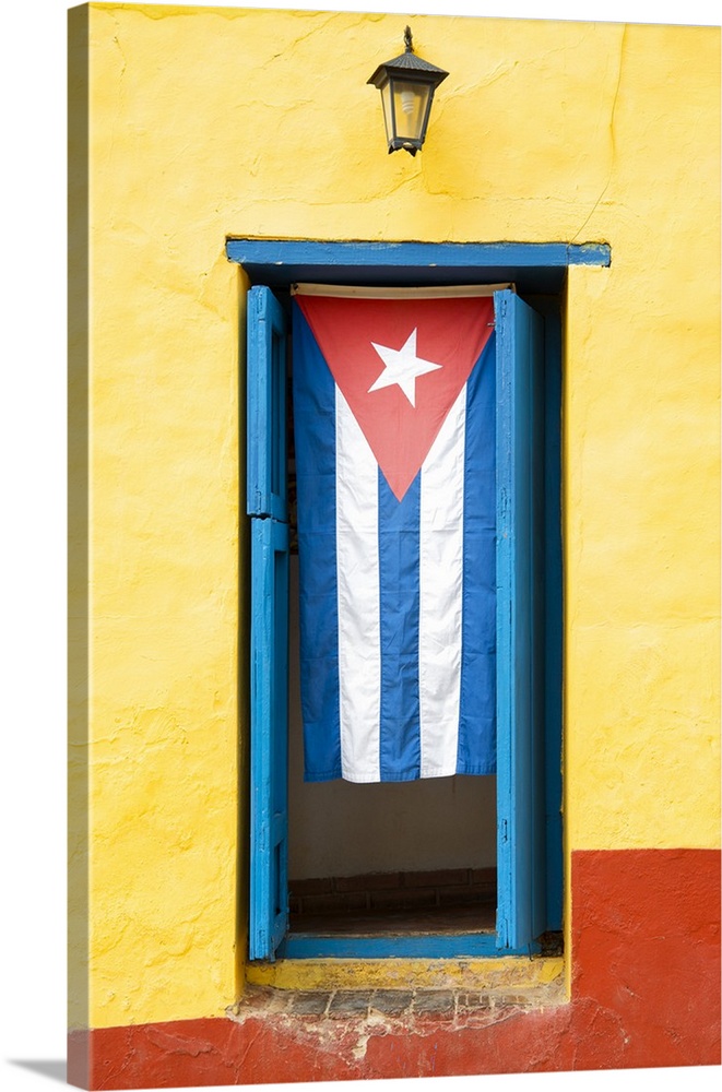 Photograph of the Cuban flag hanging in a window on a yellow and red wall in Havana.