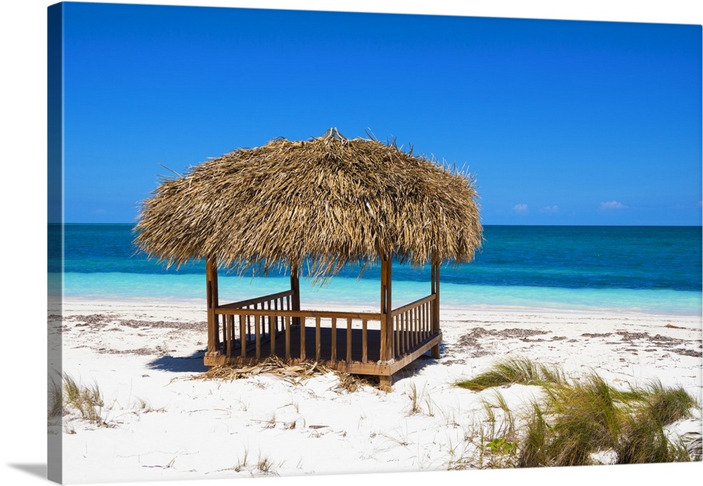 Landscape photograph of a relaxing cabana on the white sands of a Cuban beach with crystal blue waters in the distance.