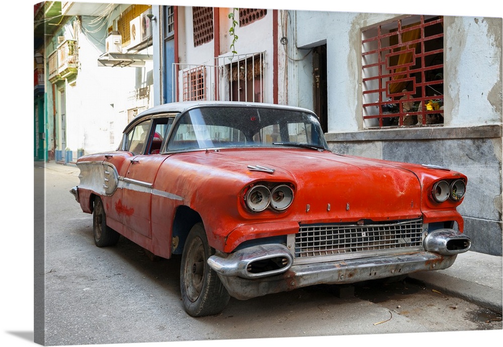 Photograph of an old beat up red car parked on the streets of Havana.
