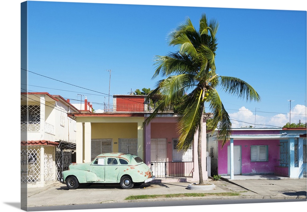 Photograph of an old car parked in font of a house in Cuba.