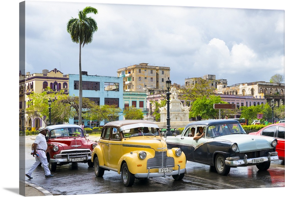 Photograph of a cloudy sky above a wet Havana street scene with vintage cars and taxis.