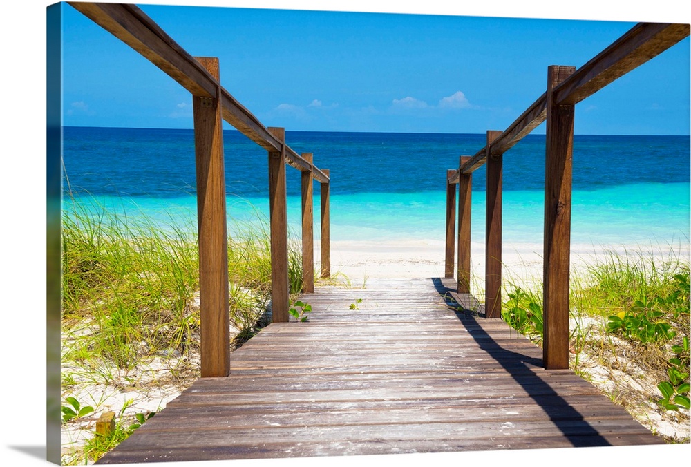 Photograph of a wooden walkway leading straight to the white sands and crystal blue waters of a beach in Cuba.
