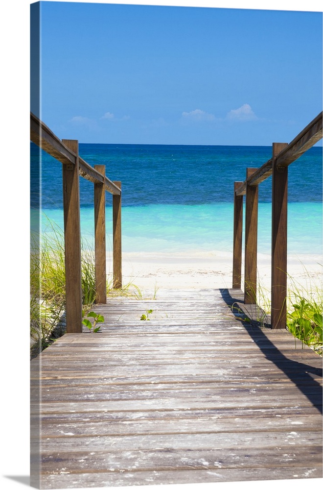Photograph of a wooden walkway leading onto a beach in Cuba with crystal blue waters.