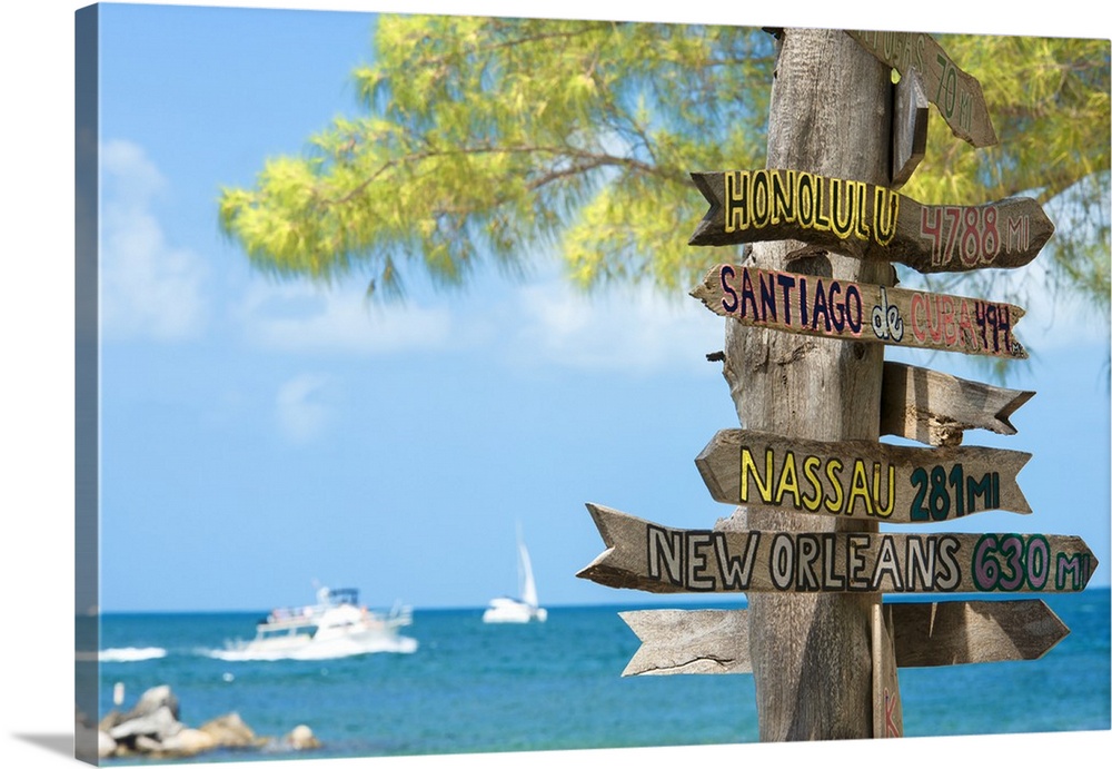 A wooden signpost full of signs showing the distances to many cities.
