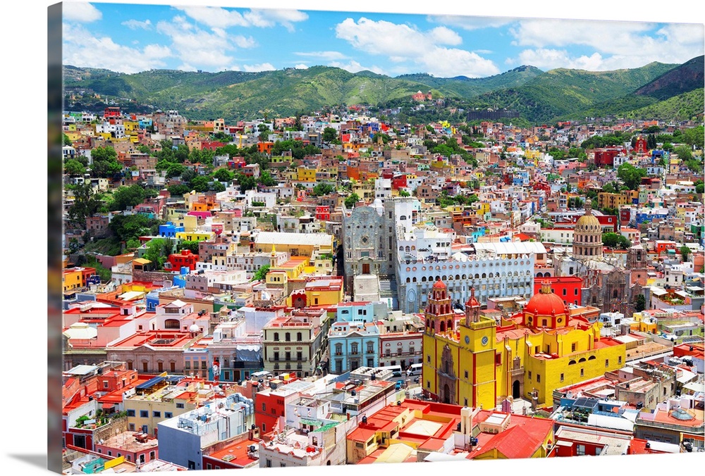 Aerial photograph of the city of Guanajuato, Mexico, with colorful buildings and mountains in the background. From the Viv...