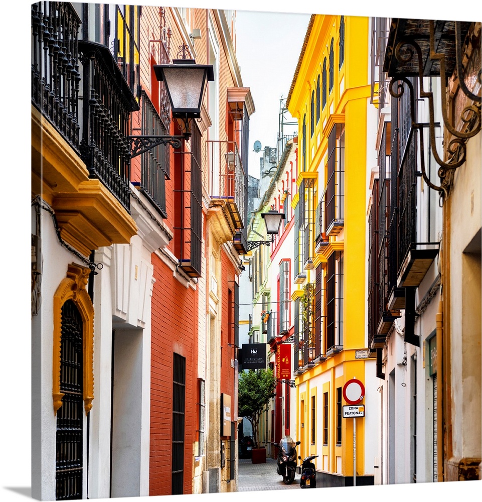 It's a traditional street with colorful facades in the city of Seville in Spain.