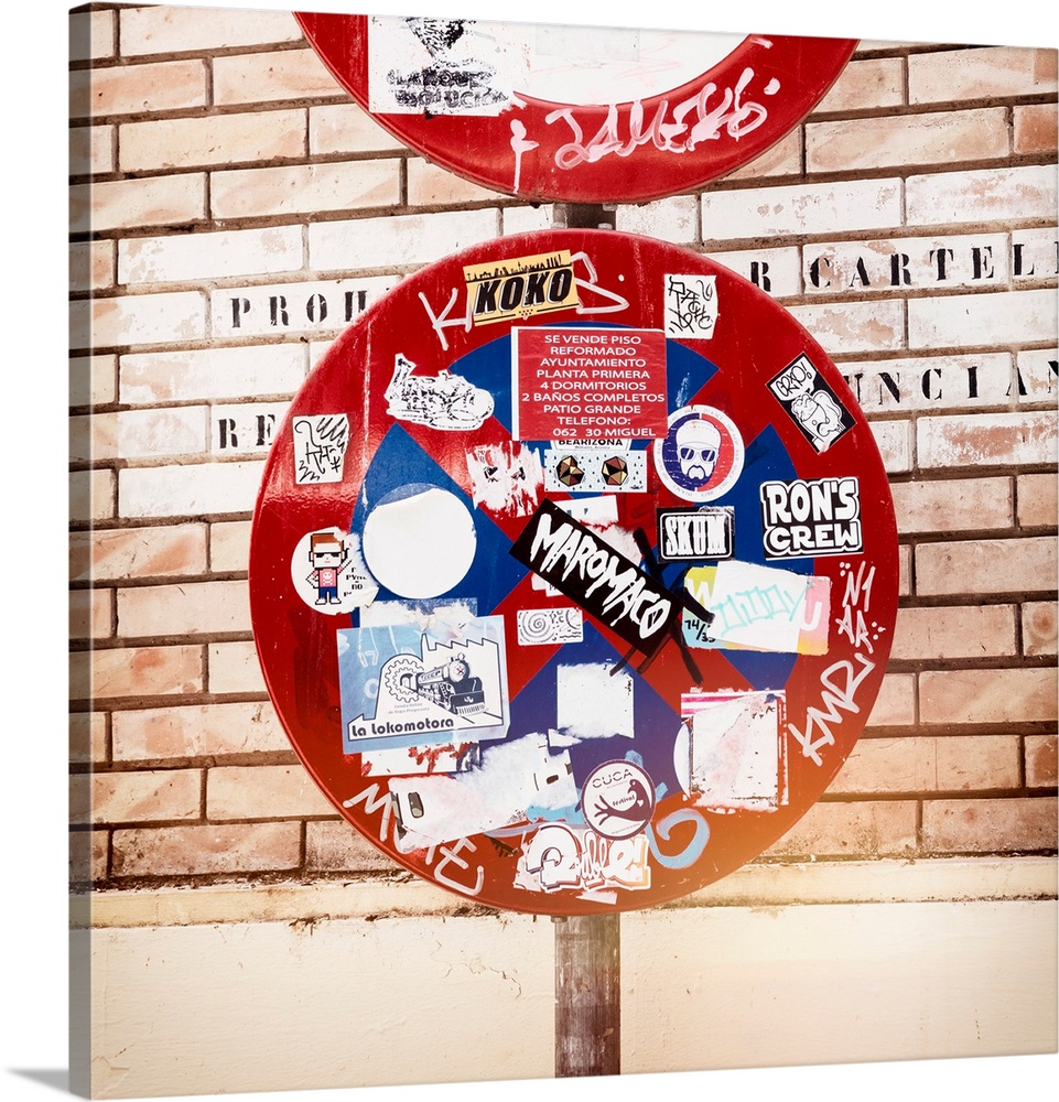 These are signposts filled with stickers in front of a brick wall in Spain.