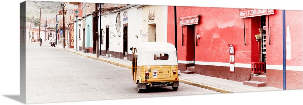 Panoramic photograph of a street scene in Mexico with a yellow tuck tuk (taxi) driving up the road. From the Viva Mexico P...