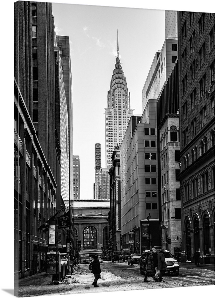 A black and white photograph of the Chrysler building standing tall in NYC, seen from street level.