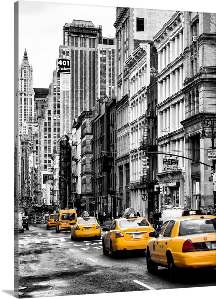 A black and white photograph of New York city with bright yellow colored taxis on the road.