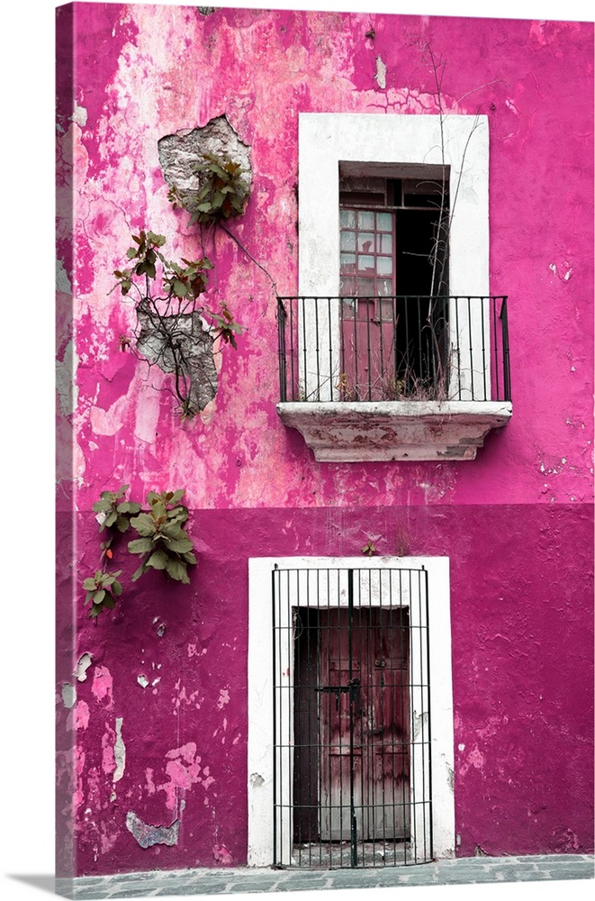 Photograph of a rustic pink wall in Mexico with peeling paint, a balcony, door, and plants growing out of the wall. From t...