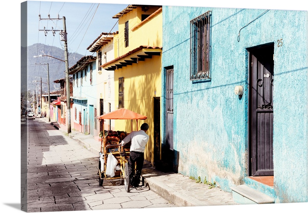 Photograph of a street vendor pushing his cart full of fresh fruit down a colorful street in Mexico. From the Viva Mexico ...