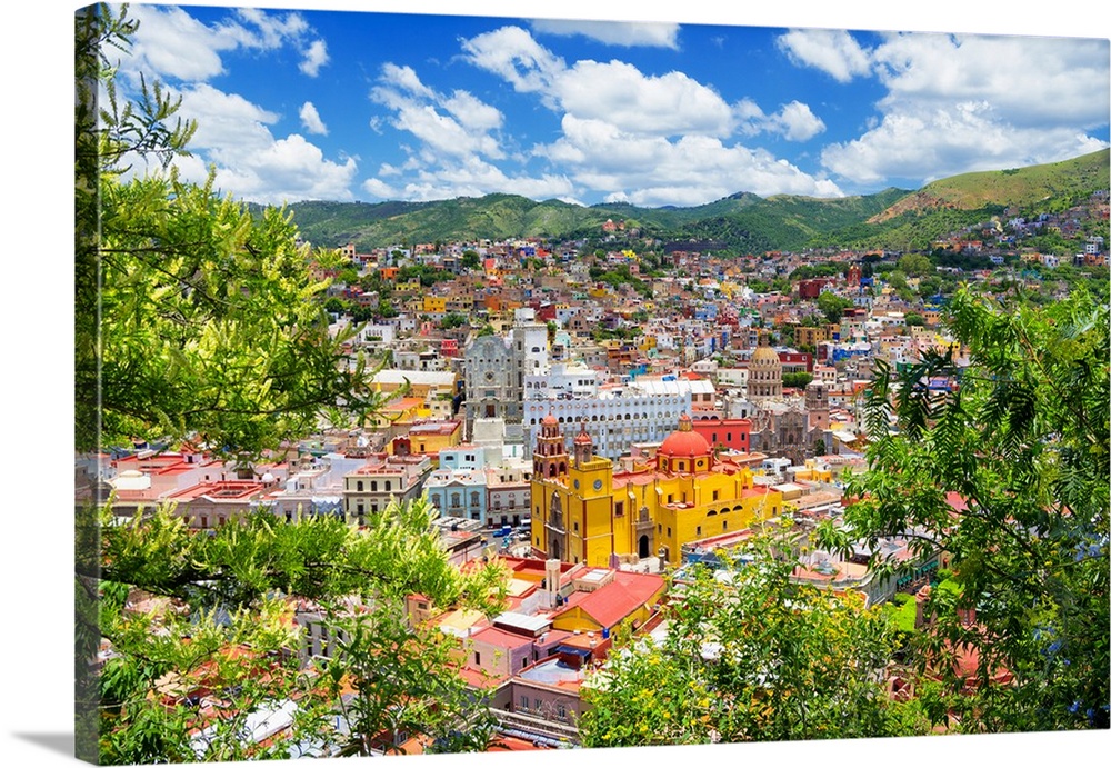 Aerial photograph of a colorful cityscape in Guanajuato, mexico, framed by lush, green trees. From the Viva Mexico Collect...