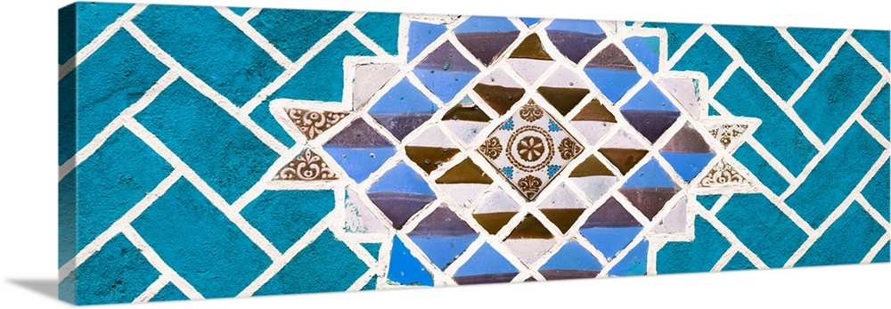Panoramic photograph of talavera tiles placed together on a wall to create a mosaic design surrounded by turquoise bricks....