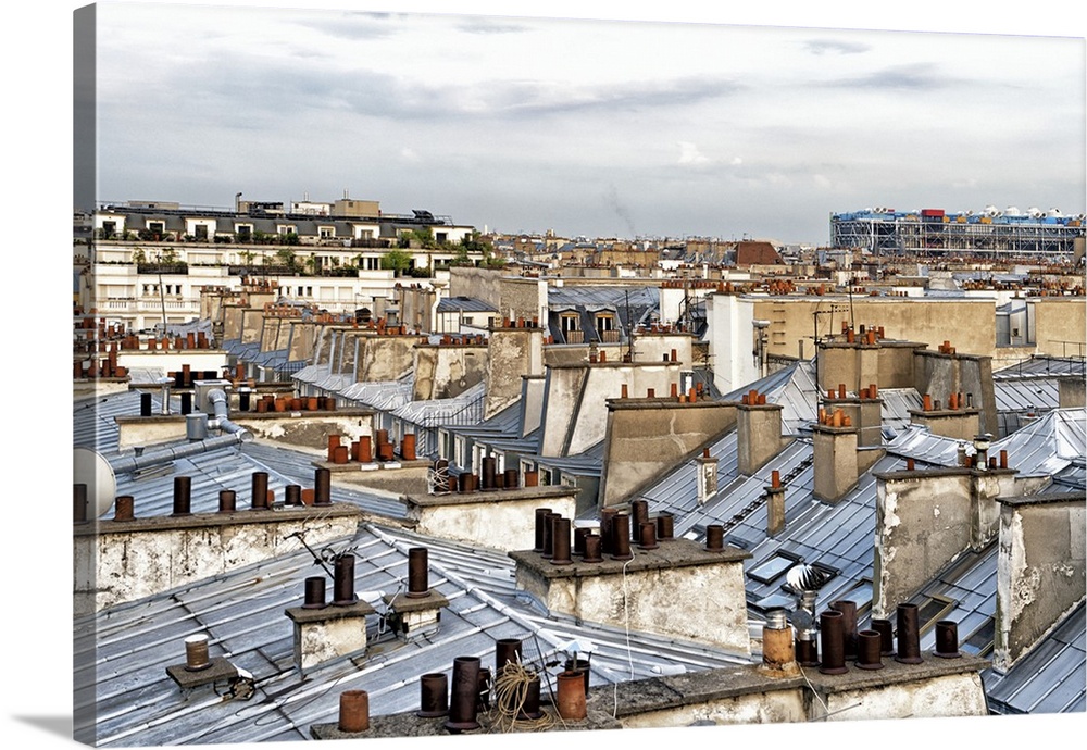 Panoramic image of the windows and grey roofs of a row of Parisian buildings with the Paris skyline in the distance.