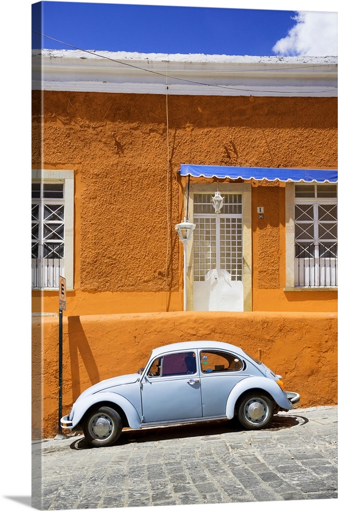 Photograph of a classic Volkswagen Beetle in front of an orange and blue building. From the Viva Mexico Collection.