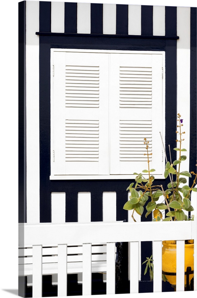 It's a white window and a bench with navy blue stripes of a house facade at Costa Nova Beach in Portugal.