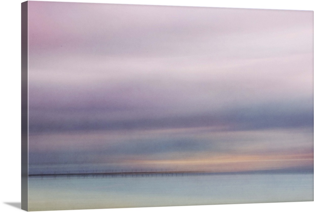 Photograph of a seascape under a blanket of smooth pale purple clouds.