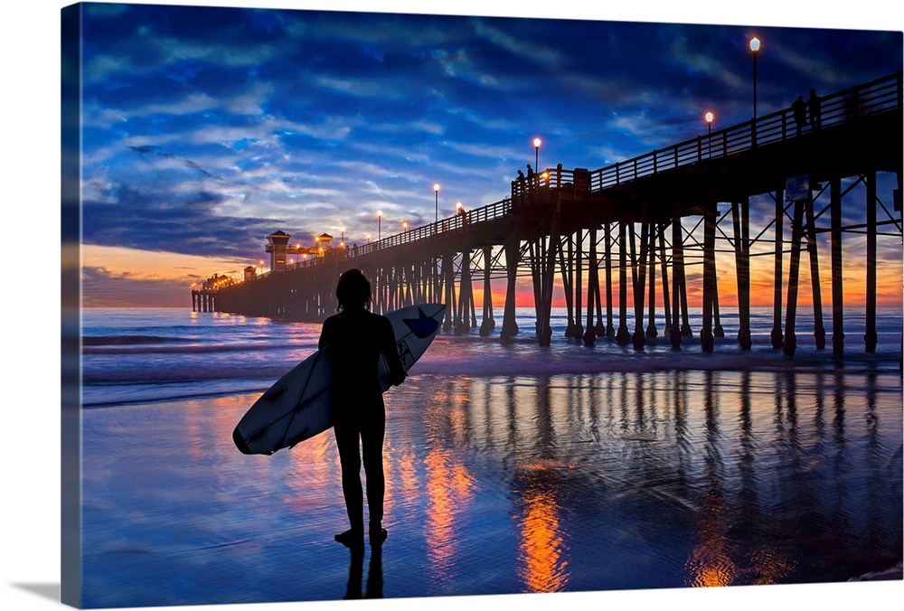A young surfer takes a moment to linger and admire a colorfully reflective sunset near the Oceanside Pier. Oceanside is 40...