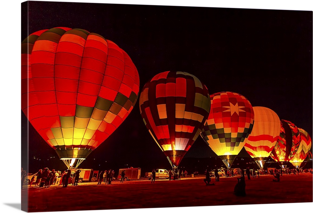 A row of hot air balloons glowing from the light inside, ready to take off at dawn.