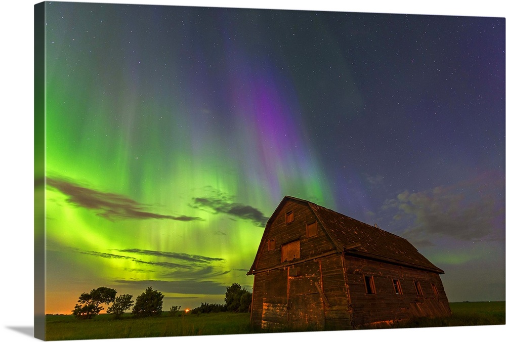 Photograph of a barn with northern lights illuminating the sky at night.