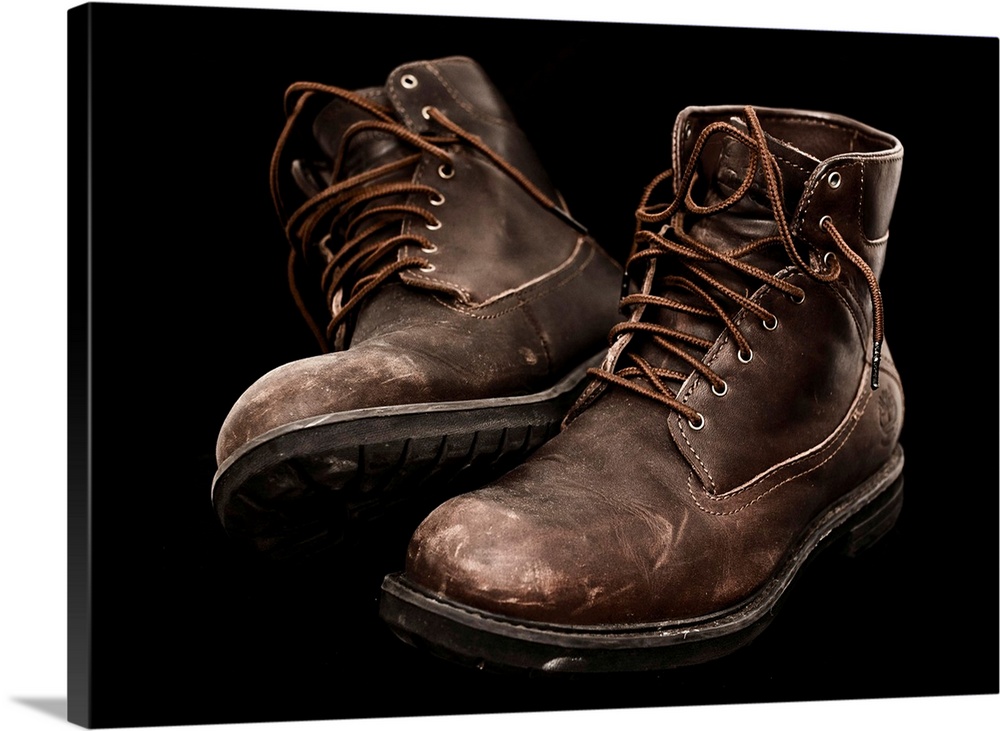 A pair of well-worn brown boots with laces.
