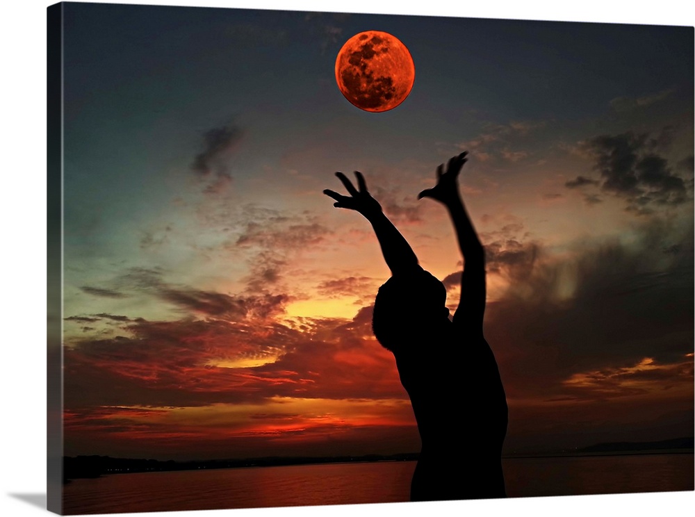 Silhouette of a person with their arms outstretched towards the red moon in the sky.