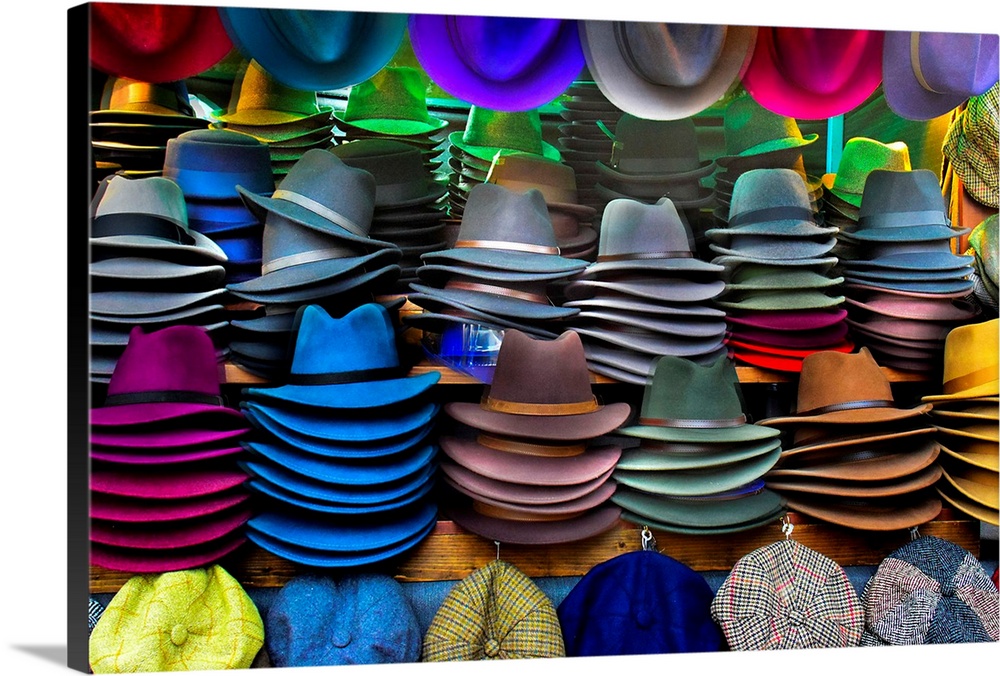 Several hats of different colors available for sale at a market.