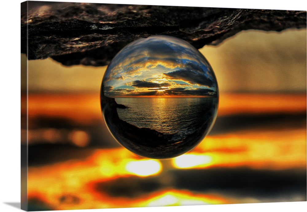 A sunset seascape reflected right-side-up in an upsidedown glass ball.