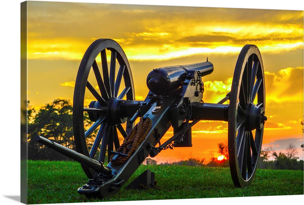 A historical cannon on an old battlefield at sunset.