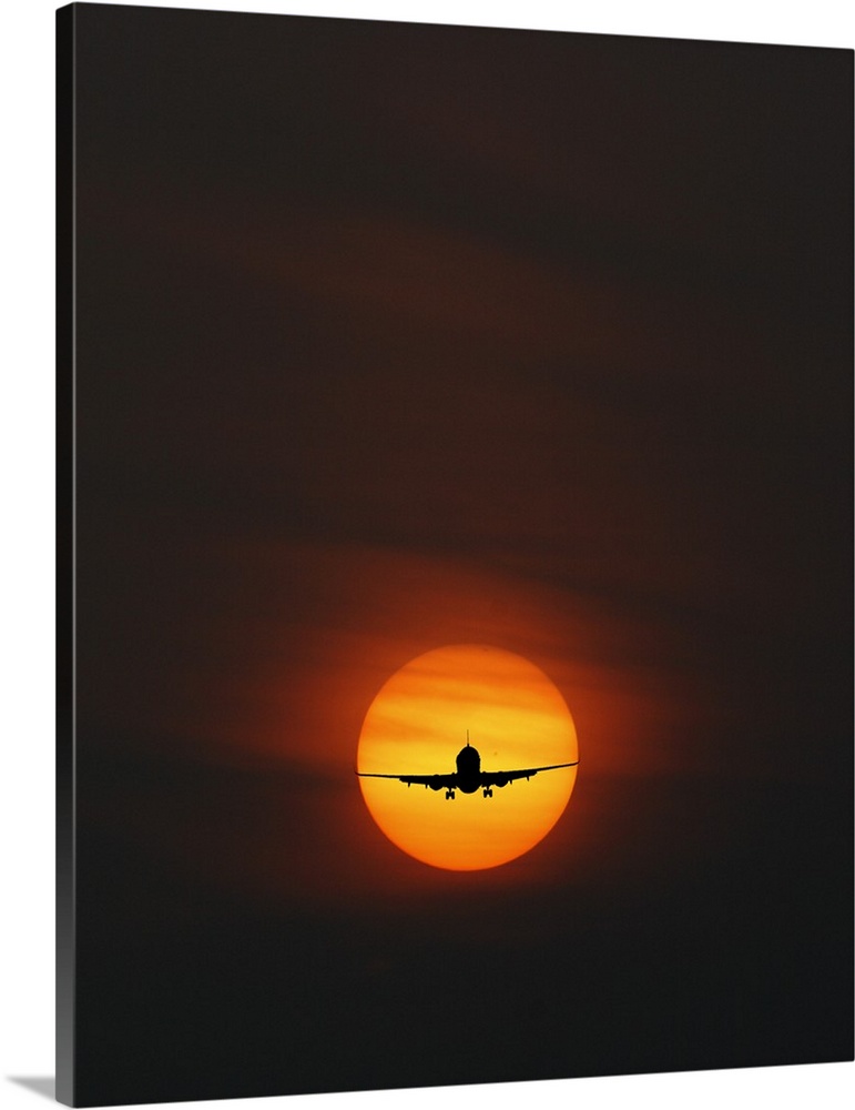 Silhouette of an airplane perfectly framed in the setting sun.