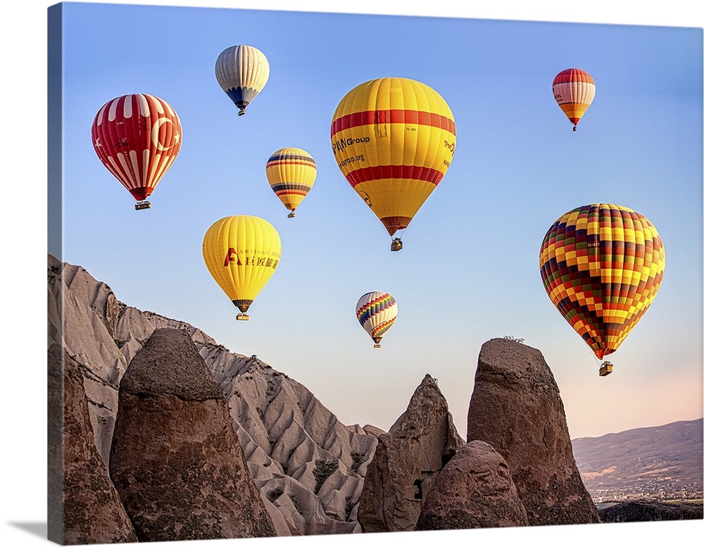 Large, colorful hot air balloons floating in the sky over Cappadocia, Turkey.