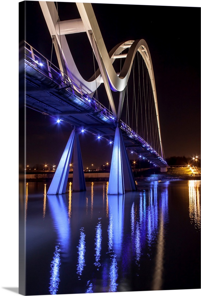 Infinity Bridge with bright blue lights reflected in the water, Stockton on Tees, England.