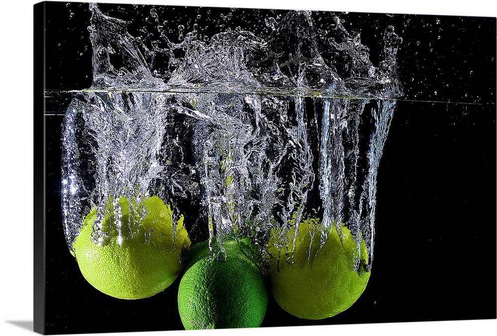 Lemons and limes splashing into clear water.