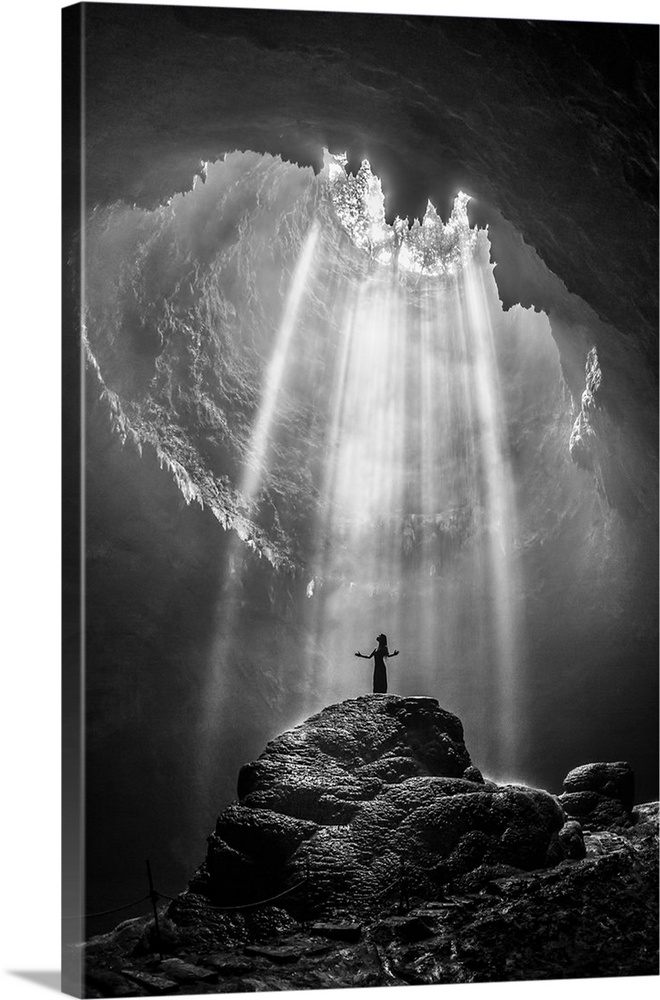 Silhouette of a person standing in a beam of sunlight in Jomblang Cave, Indonesia.