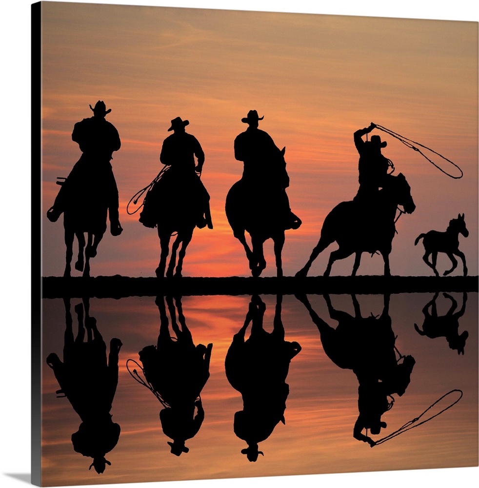Silhouettes of four cowboys on horseback at sunset, roping a foal.